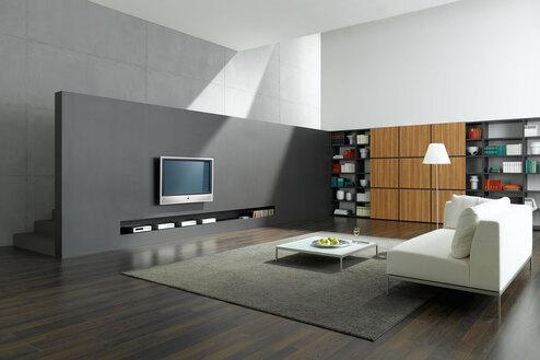 Wohnraumimpression mit Fernsehwand zur Treppe Offene Wohnraumimpression mit grauer TV-Trennwand zur Treppe und Einbauregal aus Holz und weißem Sofa