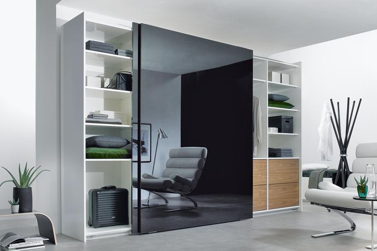 Wohnraumimpression mit abgetrennter Ruheoase Wohnraumimpression mit abgetrennter dunkler Glasschiebetür für Ruheoase und integrierten Einbauregalen